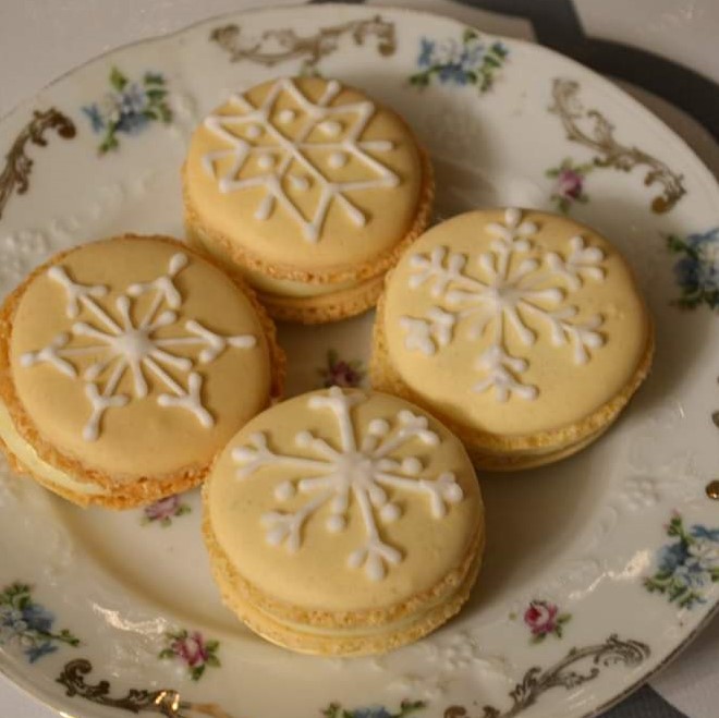 Yellow French macaron cookies with snowflake design piped on top