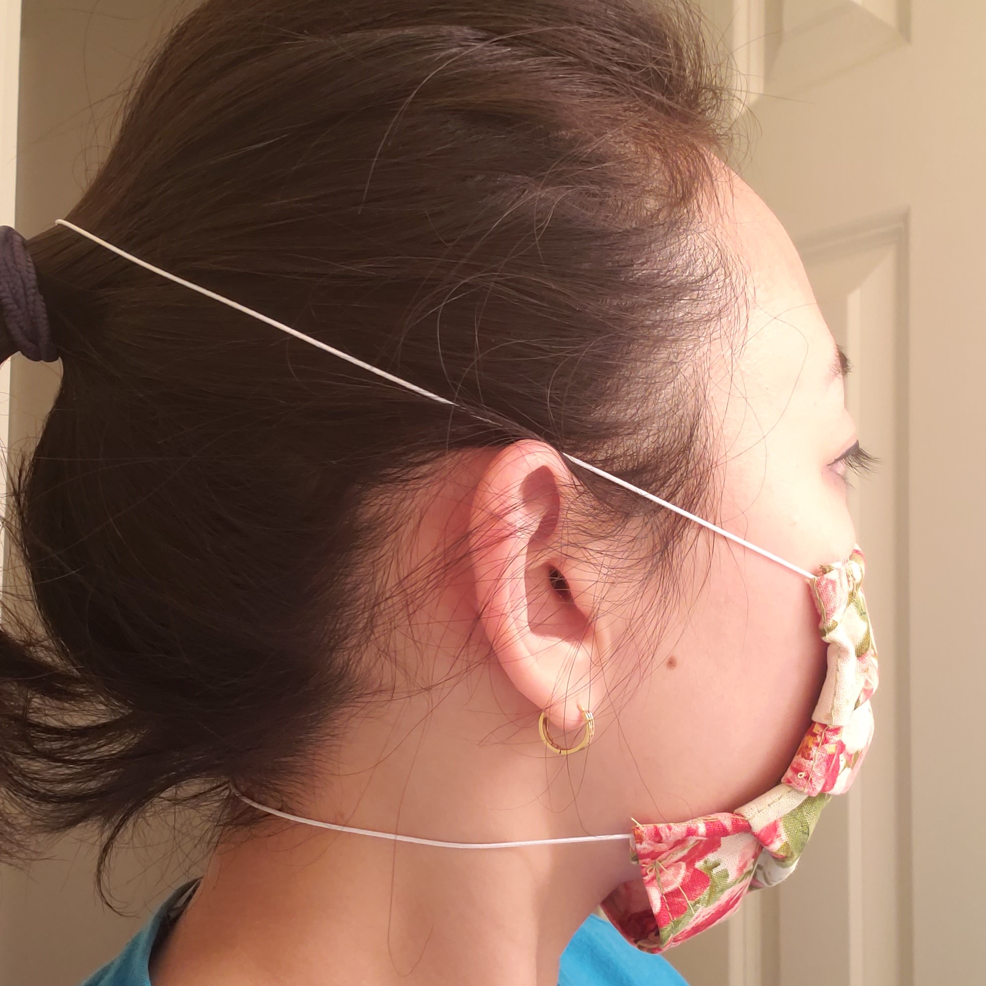 Cotton-Fabric mask with elastics strung to go over the user's head and neck, worn by a female model